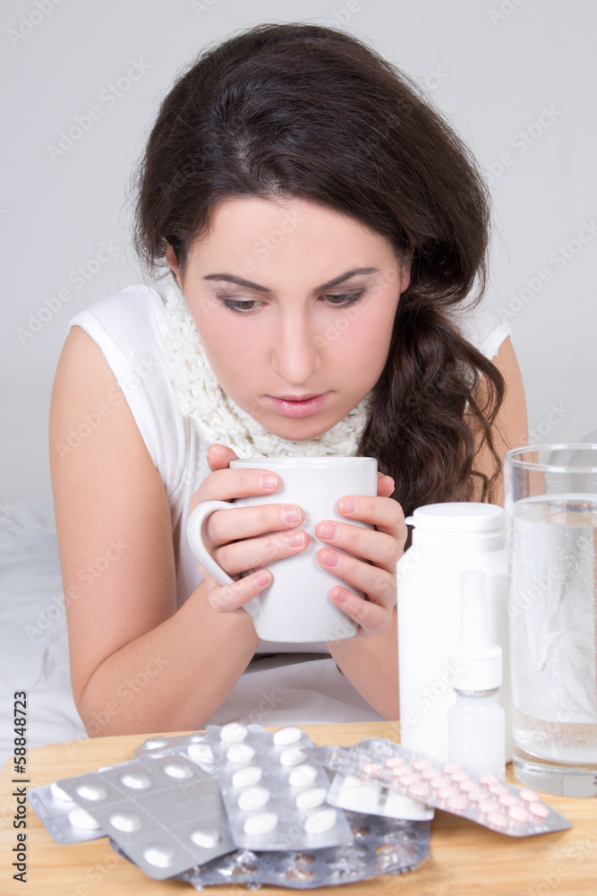 brunette woman drinking tea and pills on the table brunette woman drinking tea and pills on the table