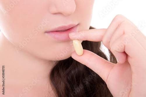 close up of young attractive woman taking pill