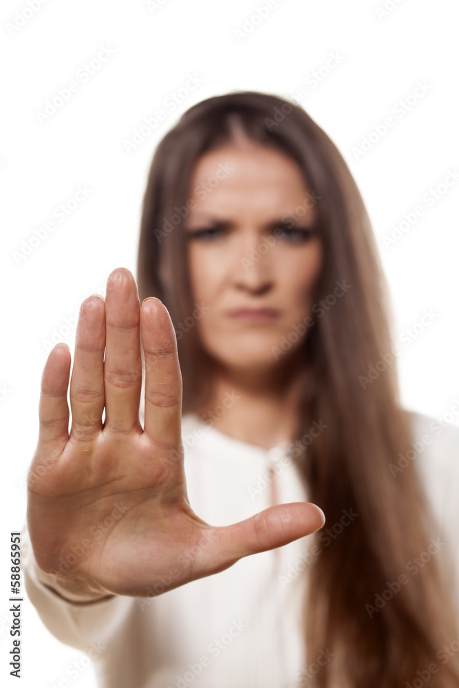scowling young woman showing stop sign with her palm scowling young woman showing stop sign with her palm