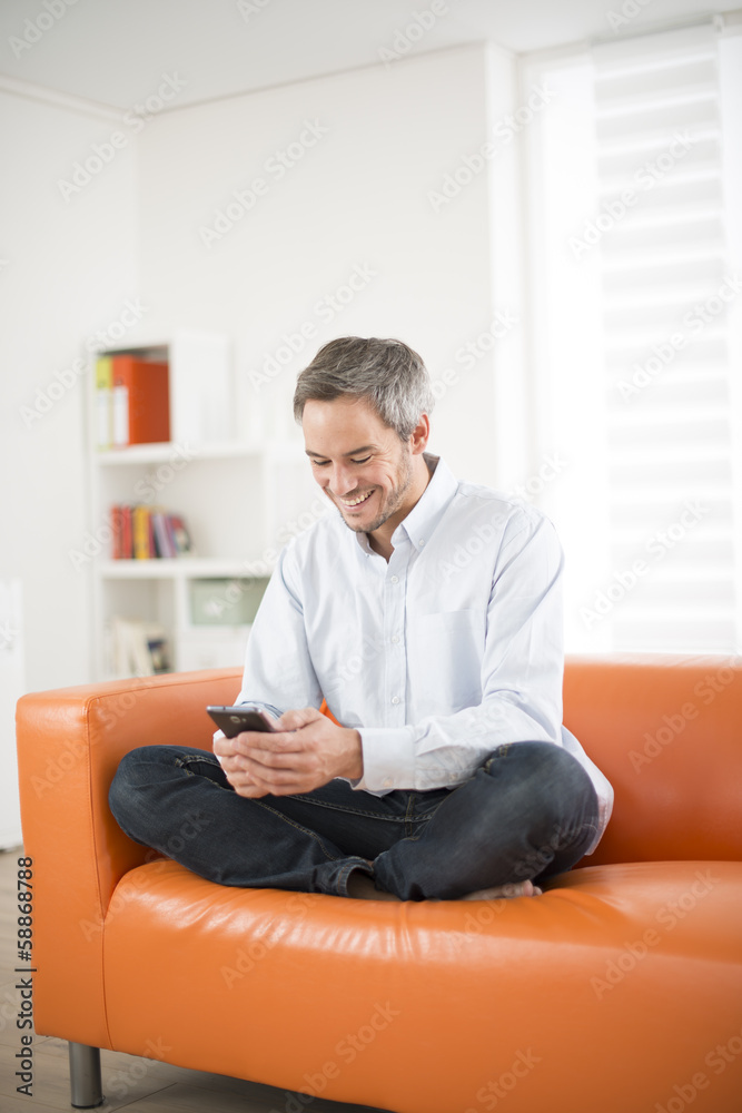 Fototapeta premium attractive man smiling and phone on a couch