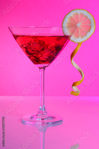 Red cocktail in martini glass on pink background