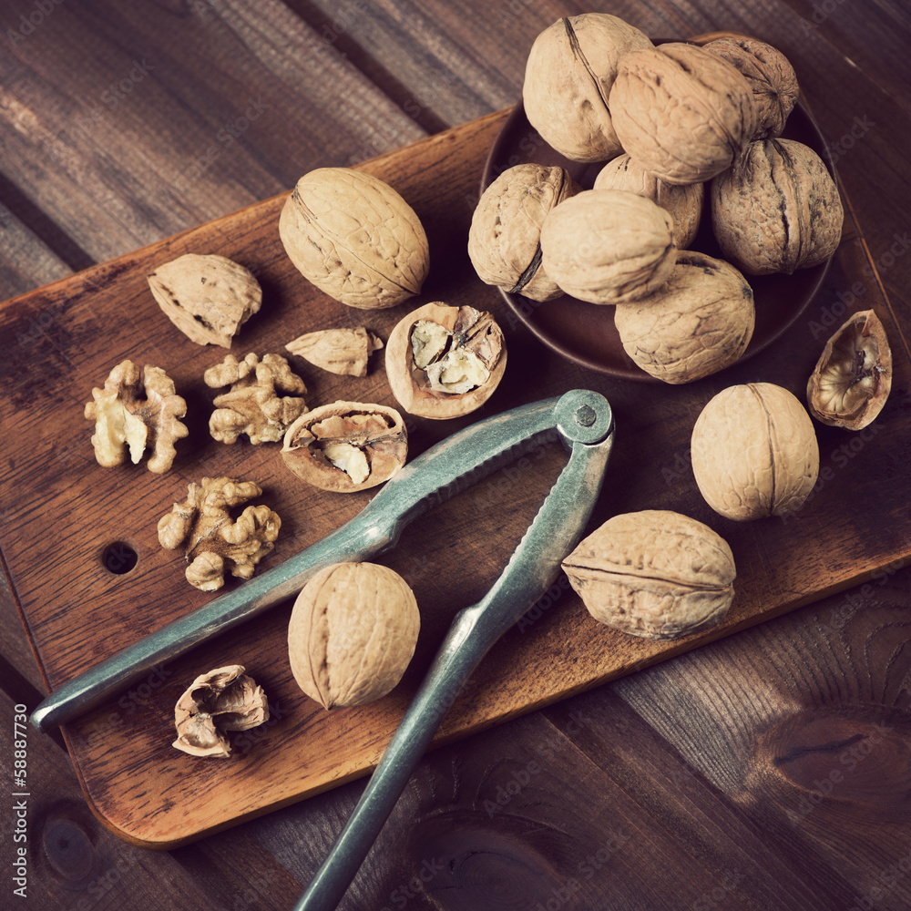 Walnuts and nutcracker on a chopping board, above view Walnuts and nutcracker on a chopping board, above view