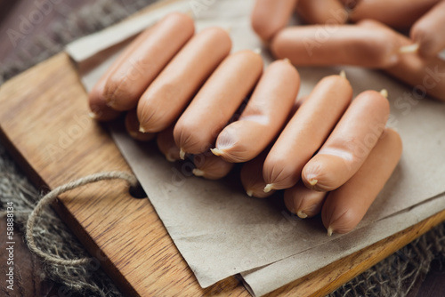 Raw sausages on a cutting board in a row, horizontal shot