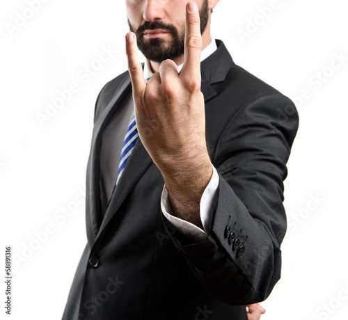 Young businessman doing the horn sign over white background