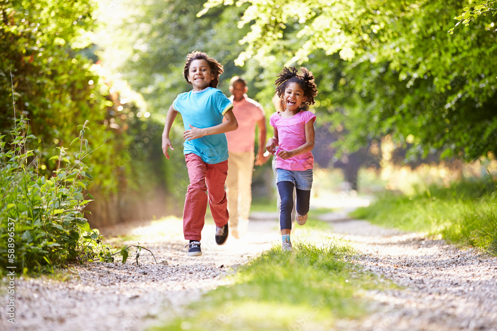 Fototapeta premium Children Running In Countryside With Father