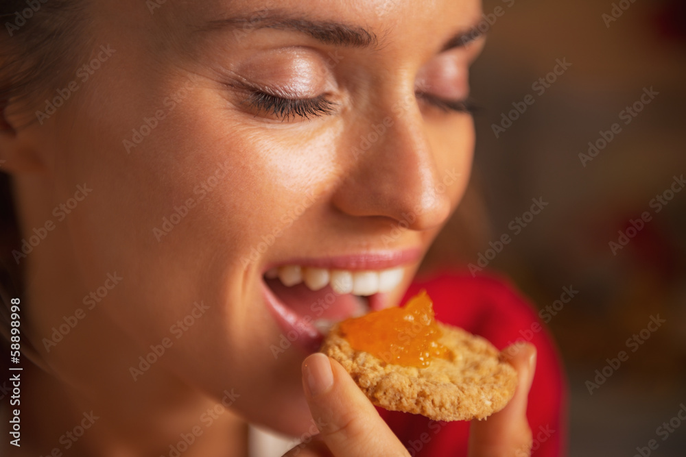 Portrait of young woman eating cookie with orange jam Portrait of young woman eating cookie with orange jam