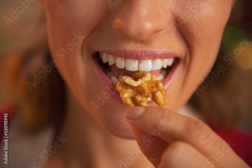 Closeup on young housewife eating walnuts
