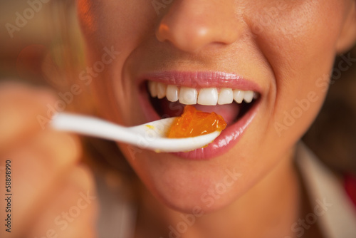 Canvas Print Closeup on happy young woman eating orange jam