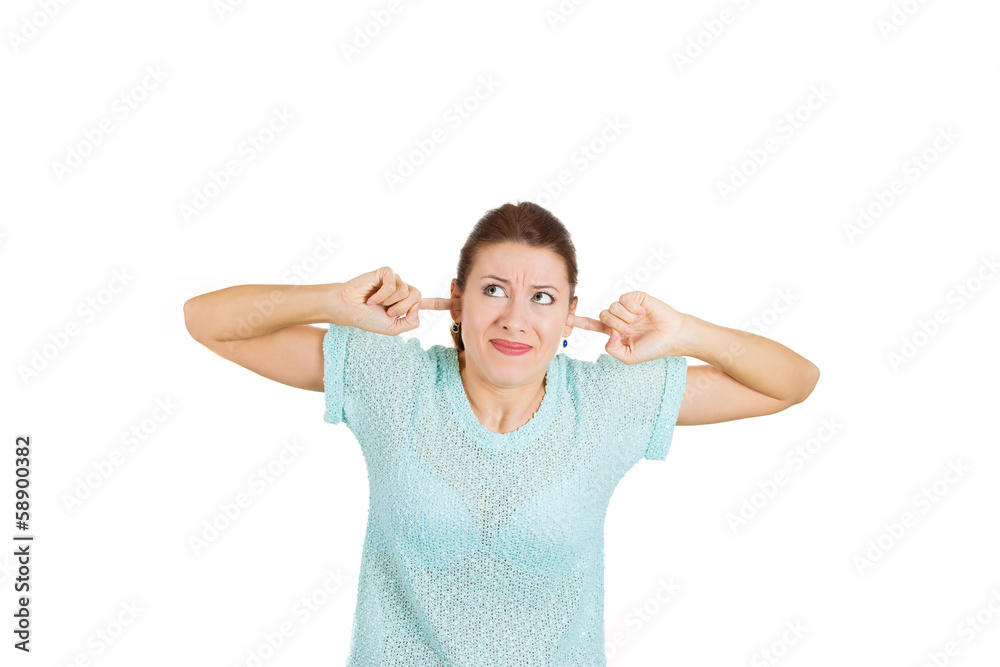 Displeased woman covering her ears from loud noise Displeased woman covering her ears from loud noise