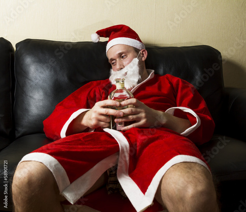 Fotografija drunk Santa Claus posing with a bottle of whisky