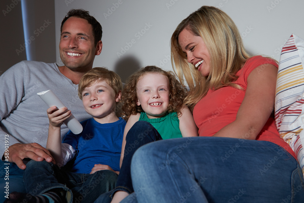 Family Sitting On Sofa Watching TV Together