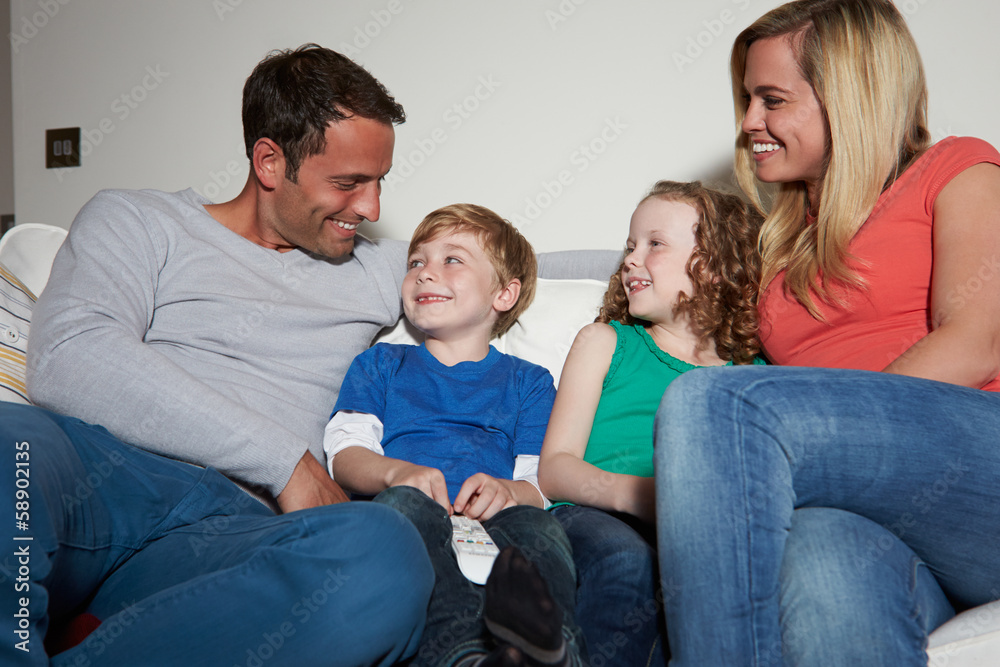 Family Sitting On Sofa Watching TV Together