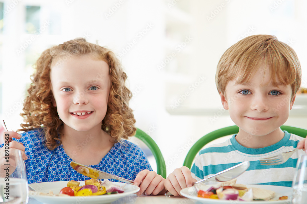 Fototapeta premium Two Children Eating Meal At Home Together