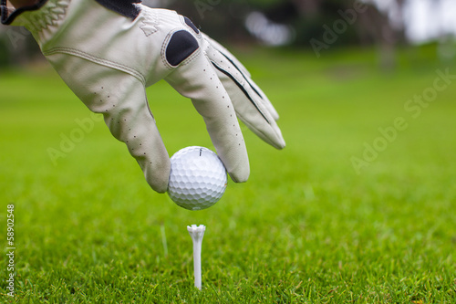 Close-up of man's Hand hold golf ball with tee on course