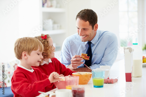 Father And Children Having Breakfast In Kitchen Together