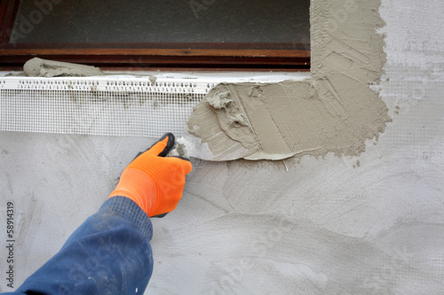 Worker spreading mortar over styrofoam insulation with trowel