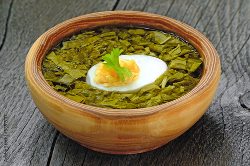 Sorrel soup with egg in brown bowl