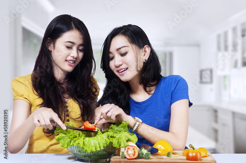 Asian women prepare salad together