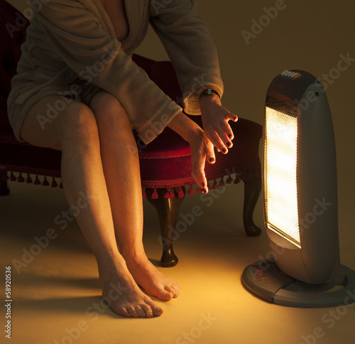 Woman keeping warm by an electric fire photo