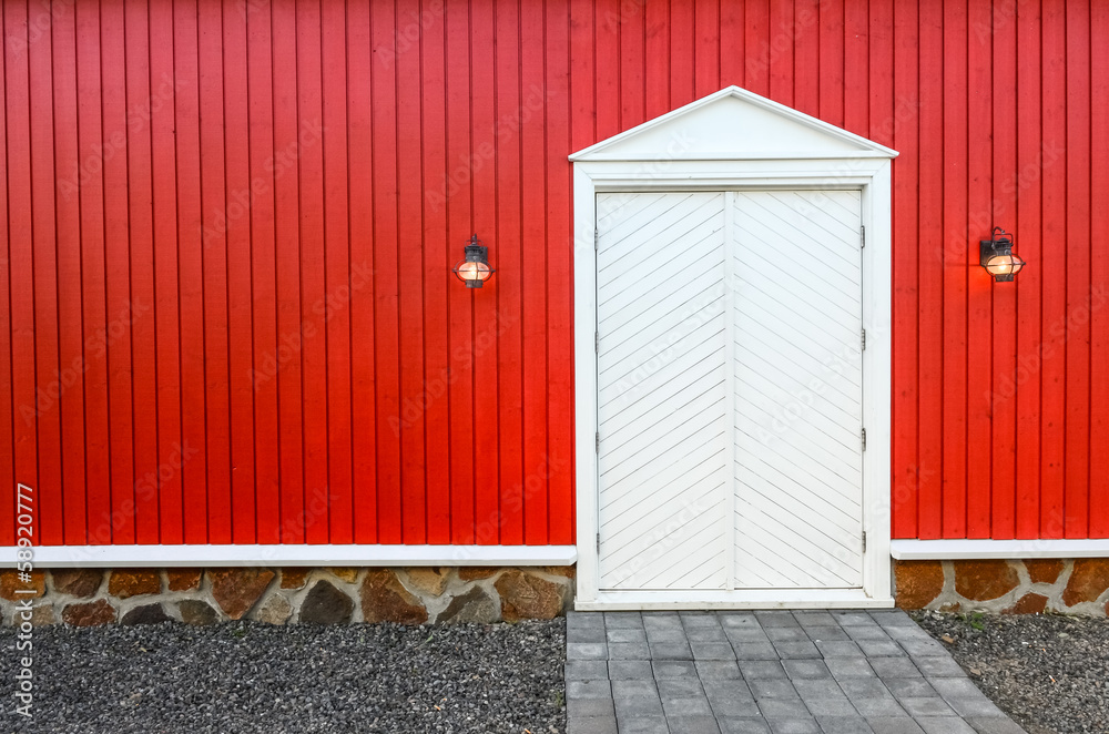 Red wooden wall and white front doors with two lamps Red wooden wall and white front doors with two lamps