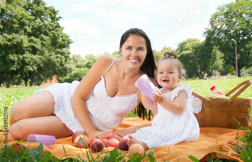 Young happy mother with daughter in the park picnicking