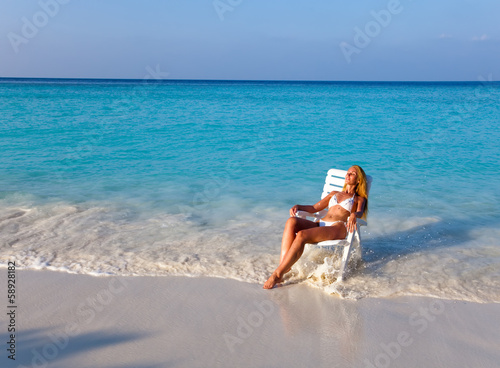 Young pretty woman in a beach chair at ocean..