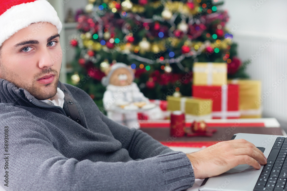 young smiling man using laptop on Christmas Eve young smiling man using laptop on Christmas Eve