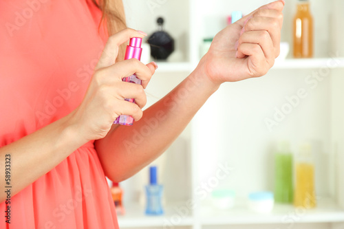 Woman testing perfume on shop windows background