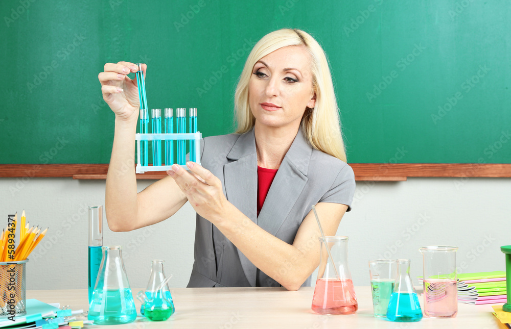 Chemistry teacher with tubes sitting at table
