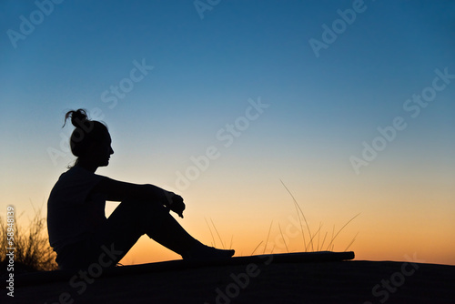 Silhouette de femme assise, soleil couchant