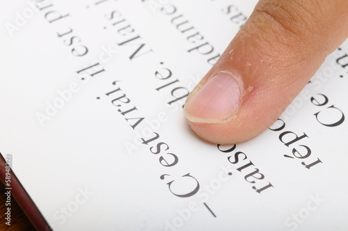 Child reading with his finger on dictionary photo