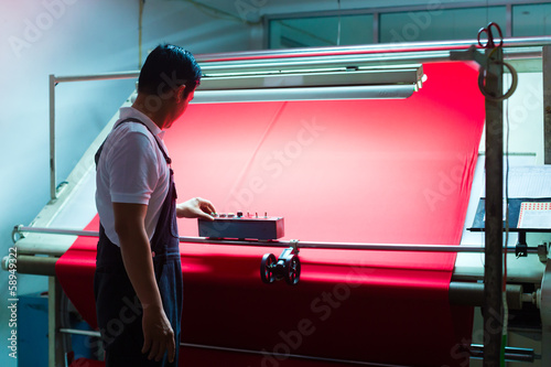 Asian worker controls fabrics in textile plant photo