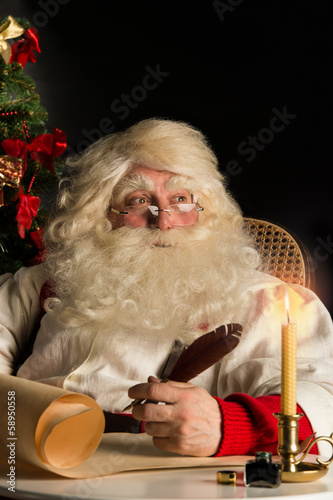 Santa Claus sitting at home and writing a letter