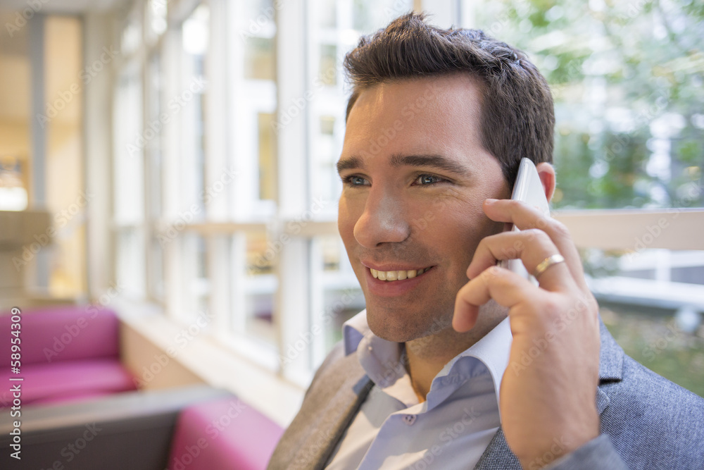Portrait of a smiling businessman using mobile phone on sofa