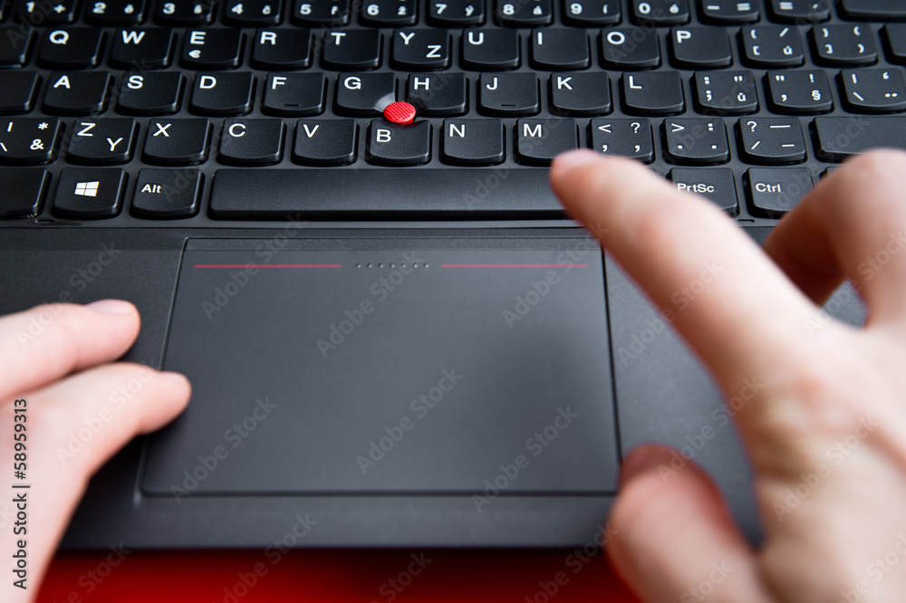 Blurred hands above the keyboard of red colored laptop Blurred hands above the keyboard of red colored laptop