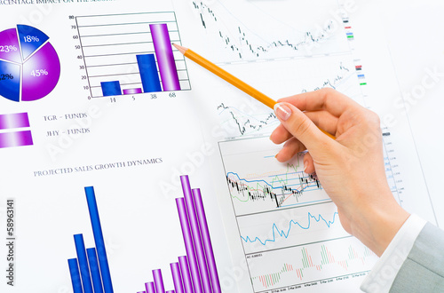 female hand pointing pencil on financial charts