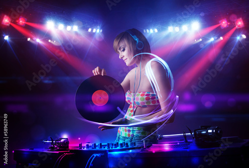 Disc jockey girl playing music with light beam effects on stage photo