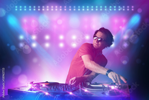 Disc jockey mixing music on turntables on stage with lights and