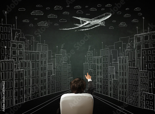 Businessman sitting in front of a cityscape drawing on a chalkbo photo