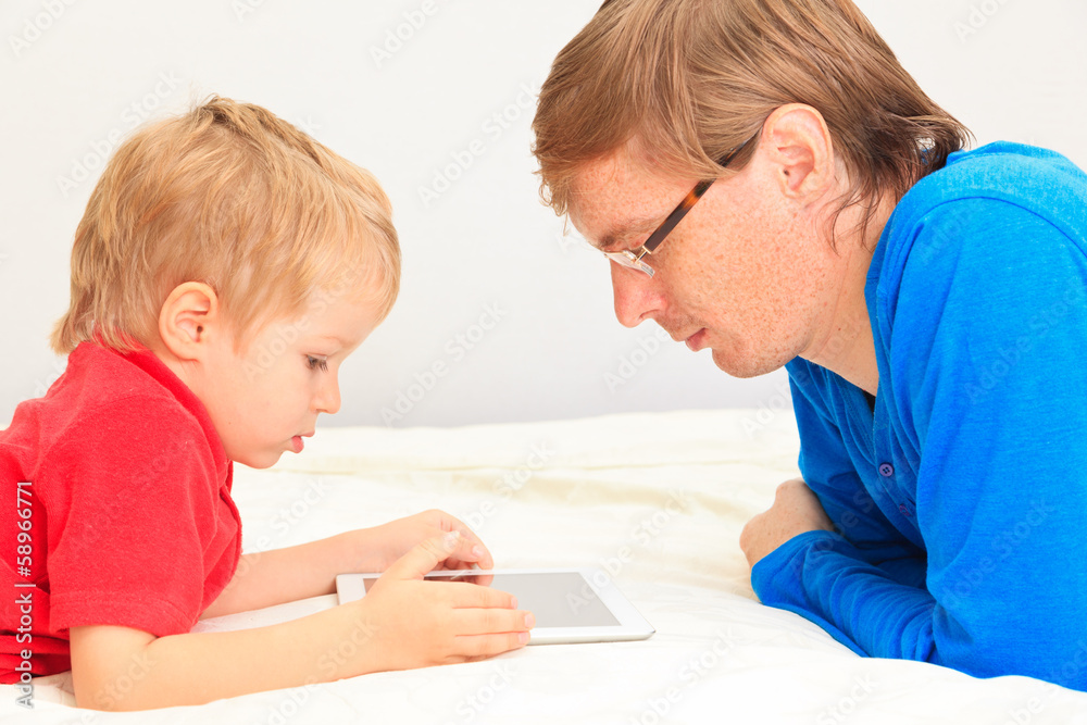 father and son looking at touch pad at home father and son looking at touch pad at home