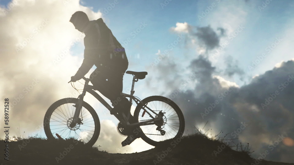 Alone bicyclist on the storm clouds background in mountain Alone bicyclist on the storm clouds background in mountain