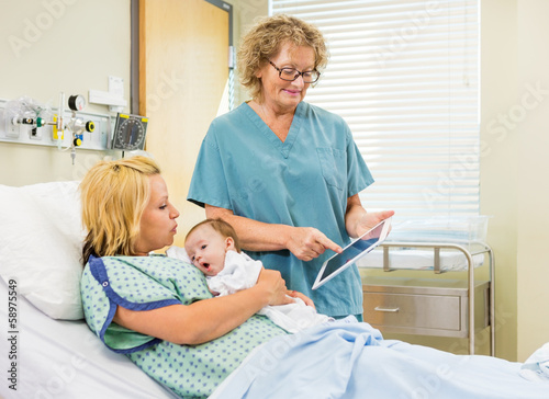 Nurse Explaining Reports On Digital Tablet To Woman With Babygir © Tyler Olson