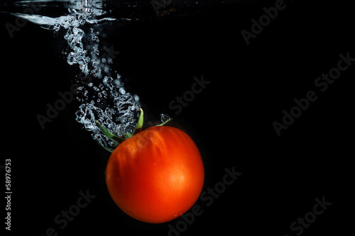 Fresh tomato dropped into water