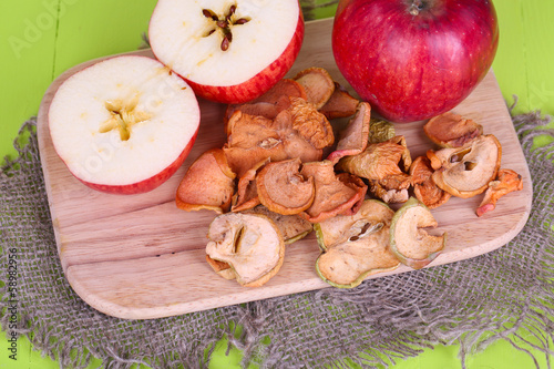 Dried apples, on cutting board, on color wooden background