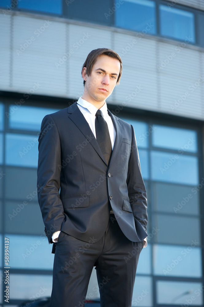 Attractive young businessman standing outside the office Attractive young businessman standing outside the office