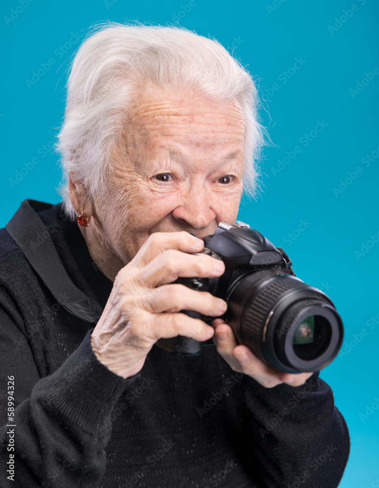 Old woman with photo camera on a blue background Old woman with photo camera on a blue background