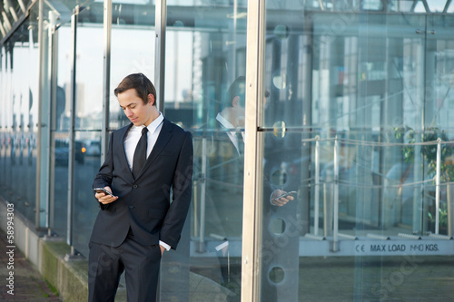 Portrait of a young businessman sending message on mobile phone