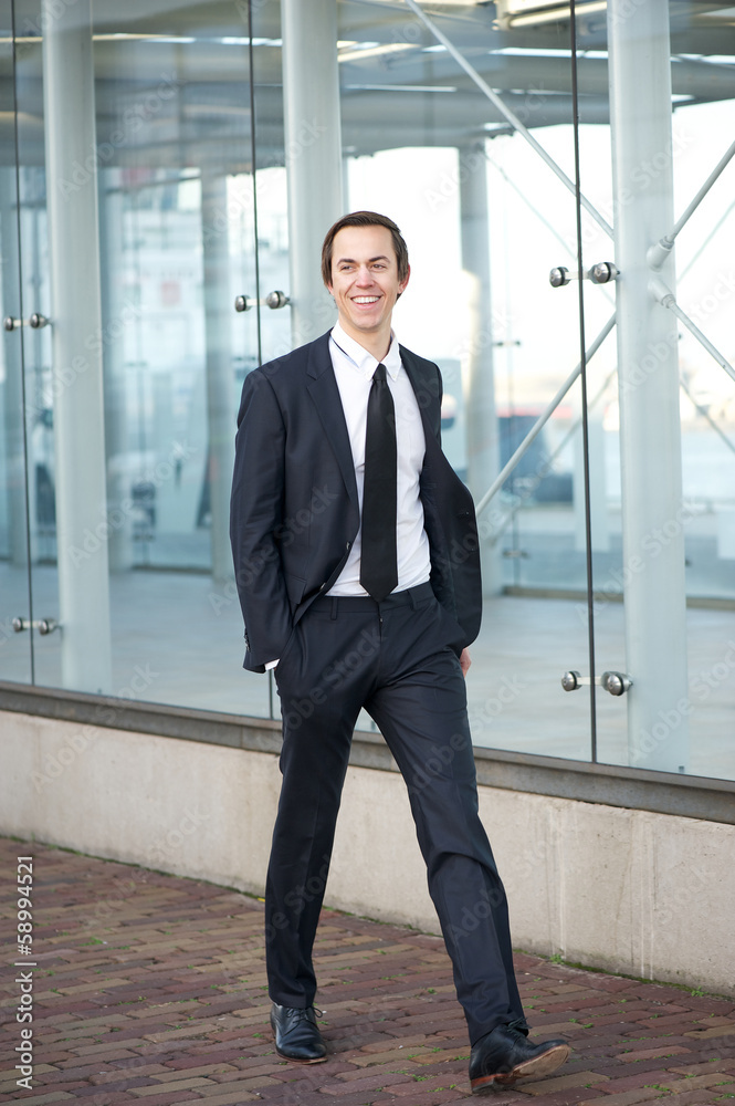 Happy businessman in suit walking on sidewalk in the city Happy businessman in suit walking on sidewalk in the city