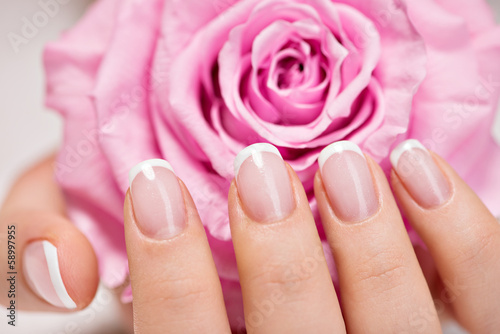 Beautiful woman's nails with french manicure  and rose