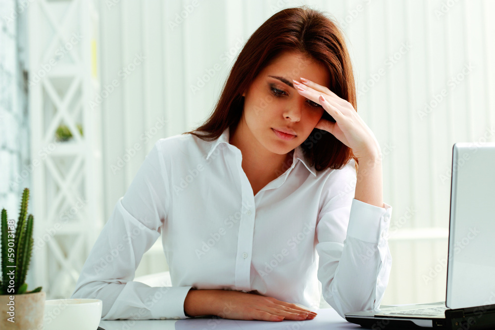 Young pensive businesswoman sitting at the table Young pensive businesswoman sitting at the table